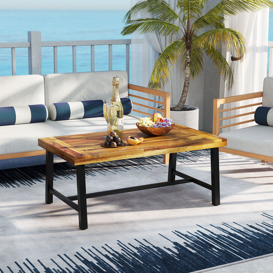 Acacia wood coffee table with heavy-duty metal legs on a patio, with decorative items and drinks on top.