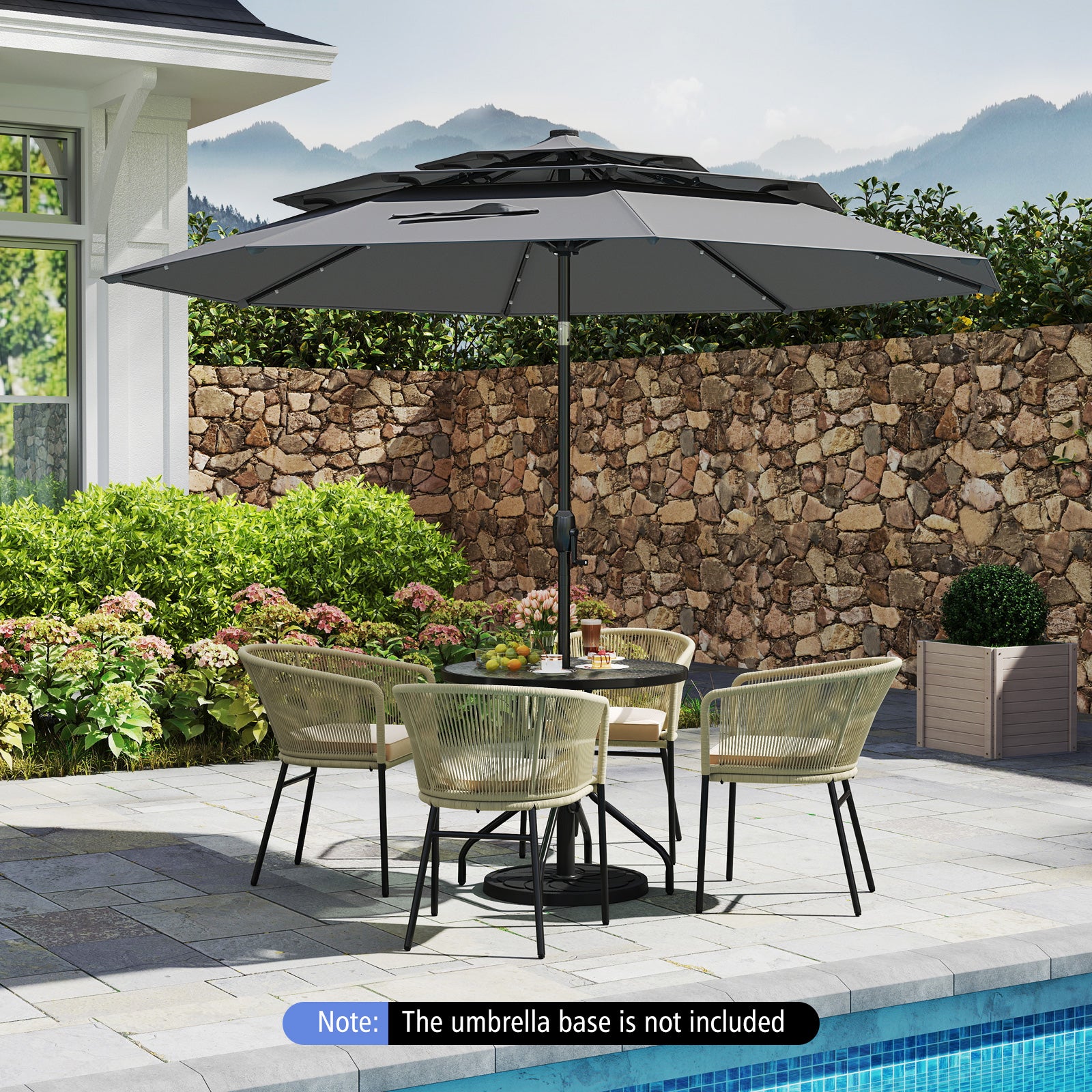 A gray 10 feet solar patio umbrella with 32 LED lights, featuring a 3-tier vented top, placed over a table and chairs set in an outdoor setting with a stone wall and pool in the background. Note: The umbrella base is not included.