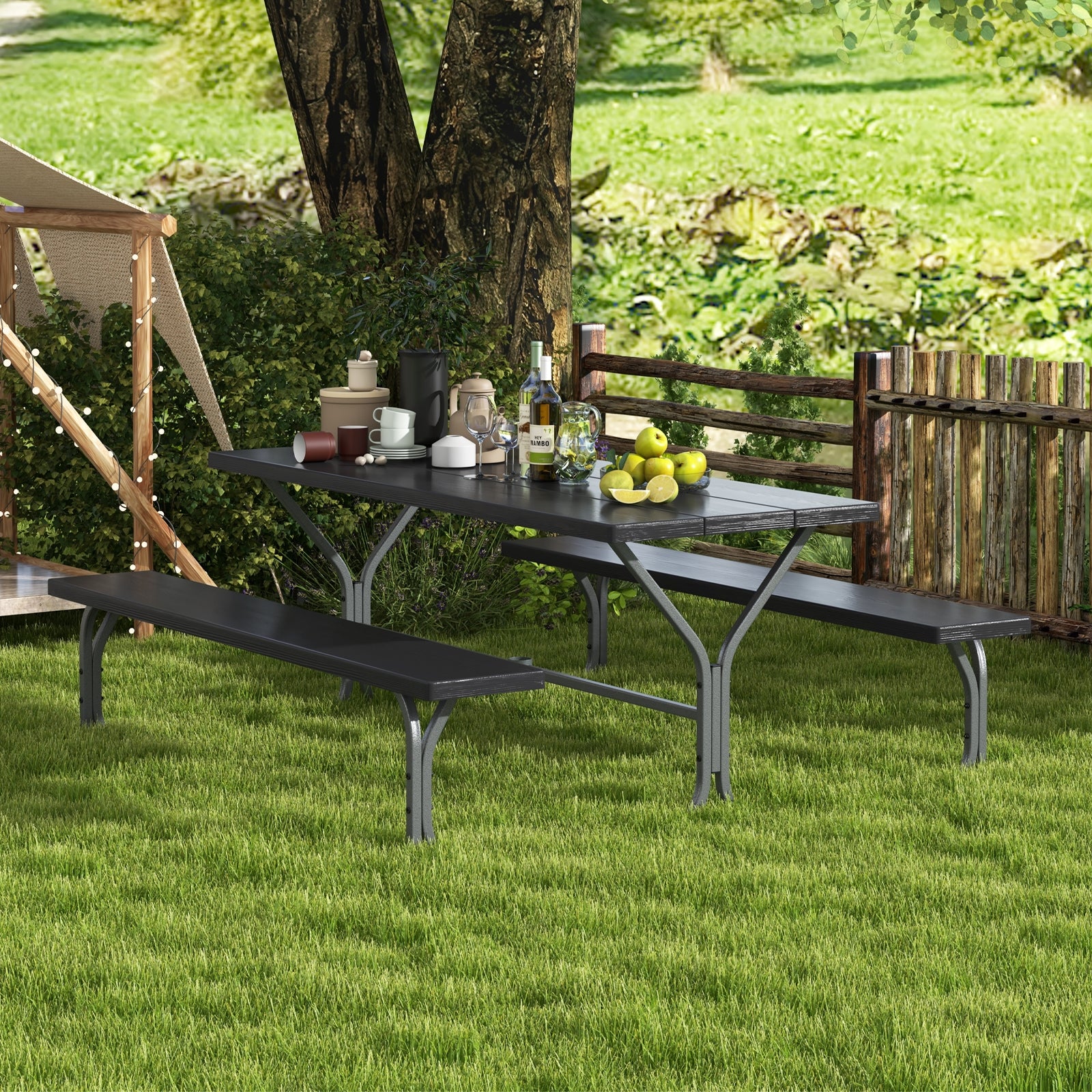 A black picnic table and bench set on a grassy outdoor area with a tablecloth, glasses, and a water bottle placed on the table.