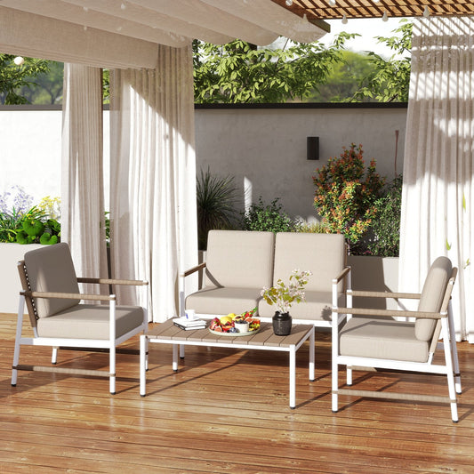 A four-piece patio furniture set with a coffee table, two single sofas, and a loveseat sofa with thick cushions, placed on a wooden deck with curtains in the background.