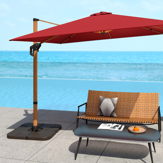 An outdoor patio scene featuring a red offset umbrella with a square-shaped base, placed on a tiled floor near a poolside bench with a cushion and a coffee table with a magazine and a bowl.