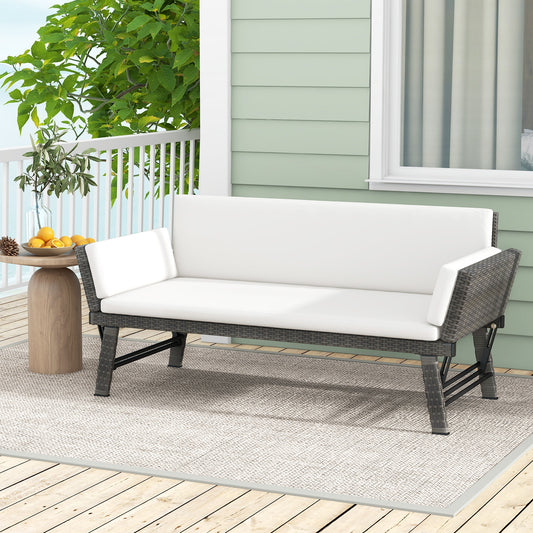 An outdoor convertible sofa daybed with adjustable armrests, featuring white cushions on a gray rattan frame, placed on a balcony with greenery in the background.