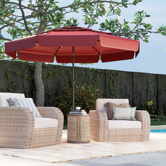A red 10 feet solar patio umbrella with a 3-tier vented top, placed over an outdoor furniture set consisting of a table and chairs, set on a patio with a wooden fence and greenery in the background.